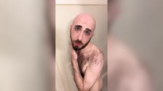 Very hairy skinny blue-eyed white guy shaves his head in the showet