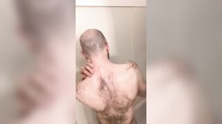 Very hairy skinny blue-eyed white guy shaves his head in the showet