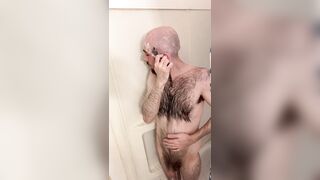 Very hairy skinny blue-eyed white guy shaves his head in the showet